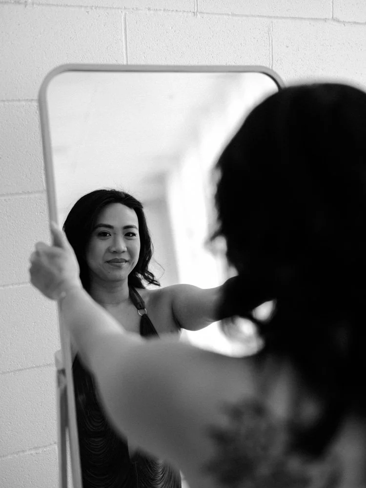 Woman in lingerie looking into a mirror with her hands resting on the glass