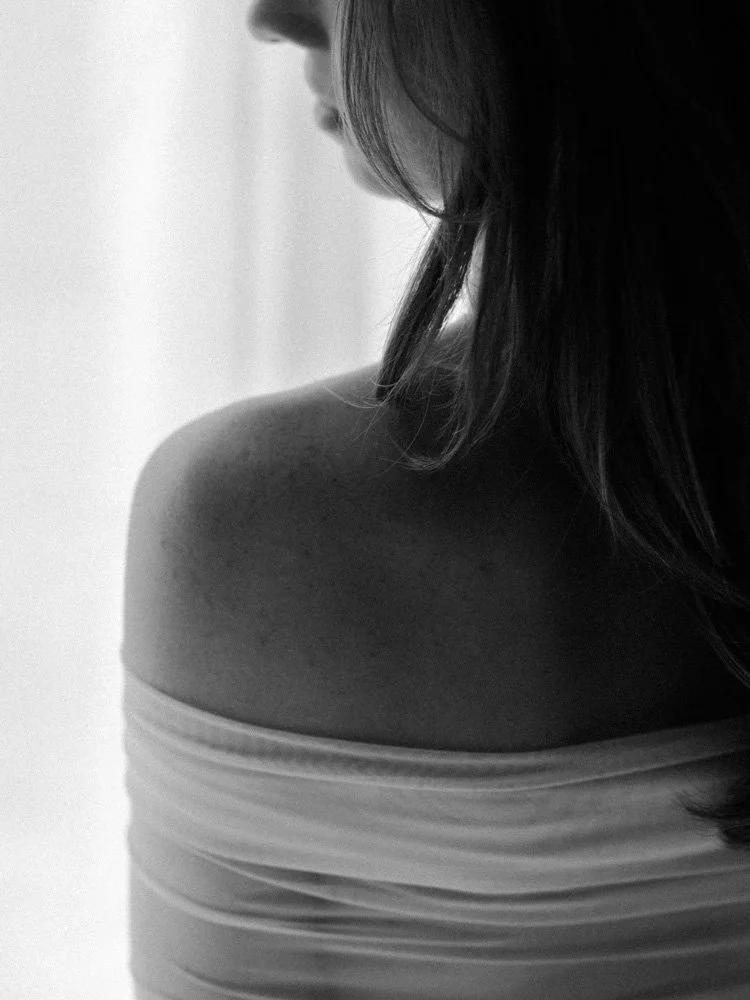Over-the-shoulder boudoir portrait with her shoulder exposed