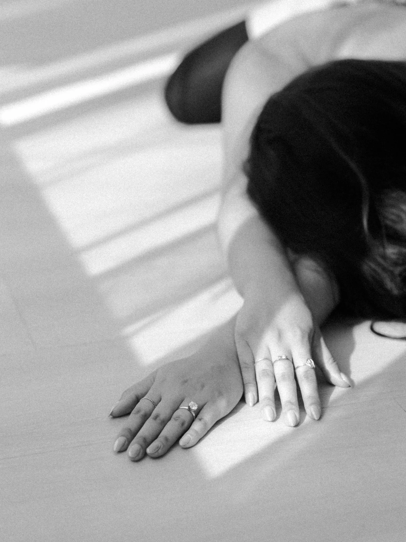Woman lying on the floor with her arms above her head and rings visible on her hand