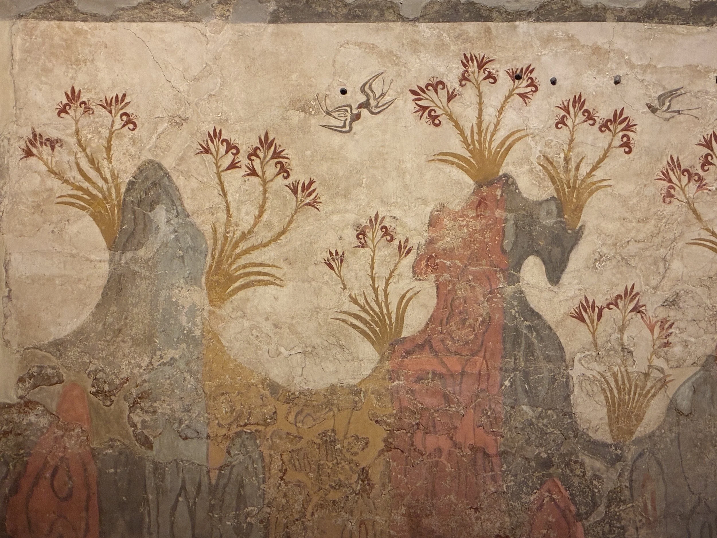 A fresco of rocky landscape with plants and birds, featuring reddish, gray, and beige tones found in the National Archaeological Museum of Greece