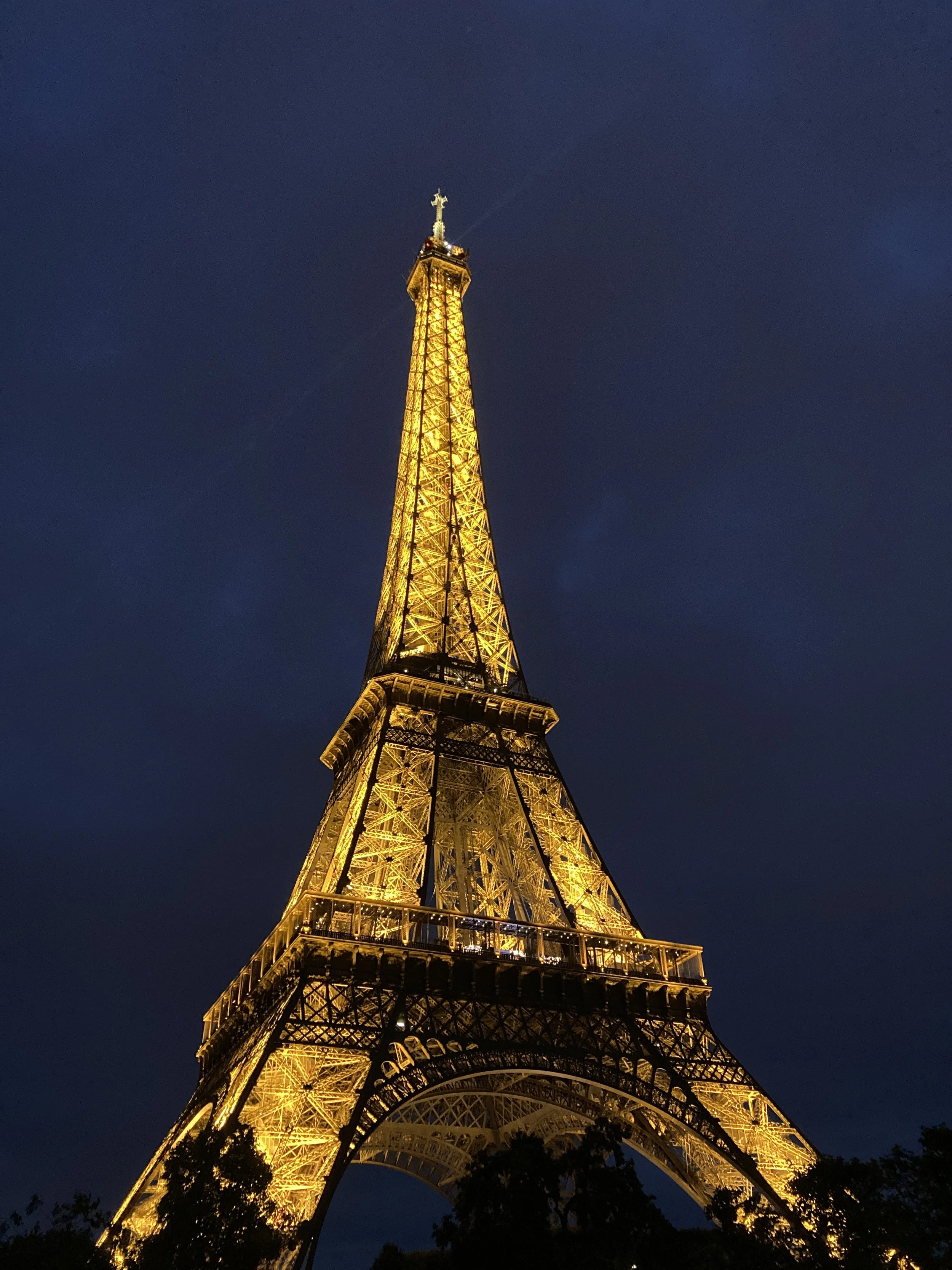 The Eiffel Tower illuminated with golden lights against a dark night sky.