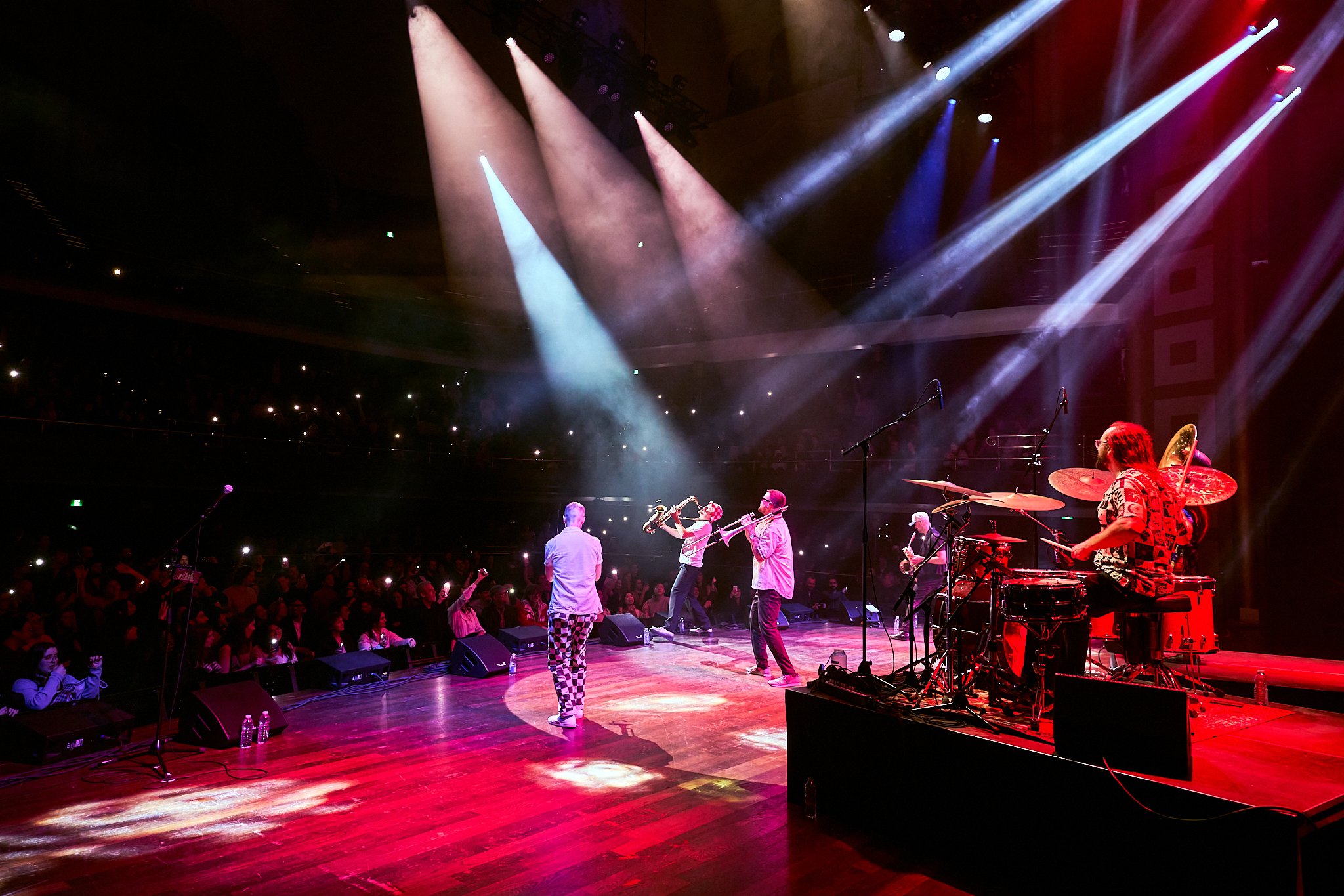 A photo of Big Smoke Brass performing at Massey Hall. The lights, haze, and energy on stage is electrifying!