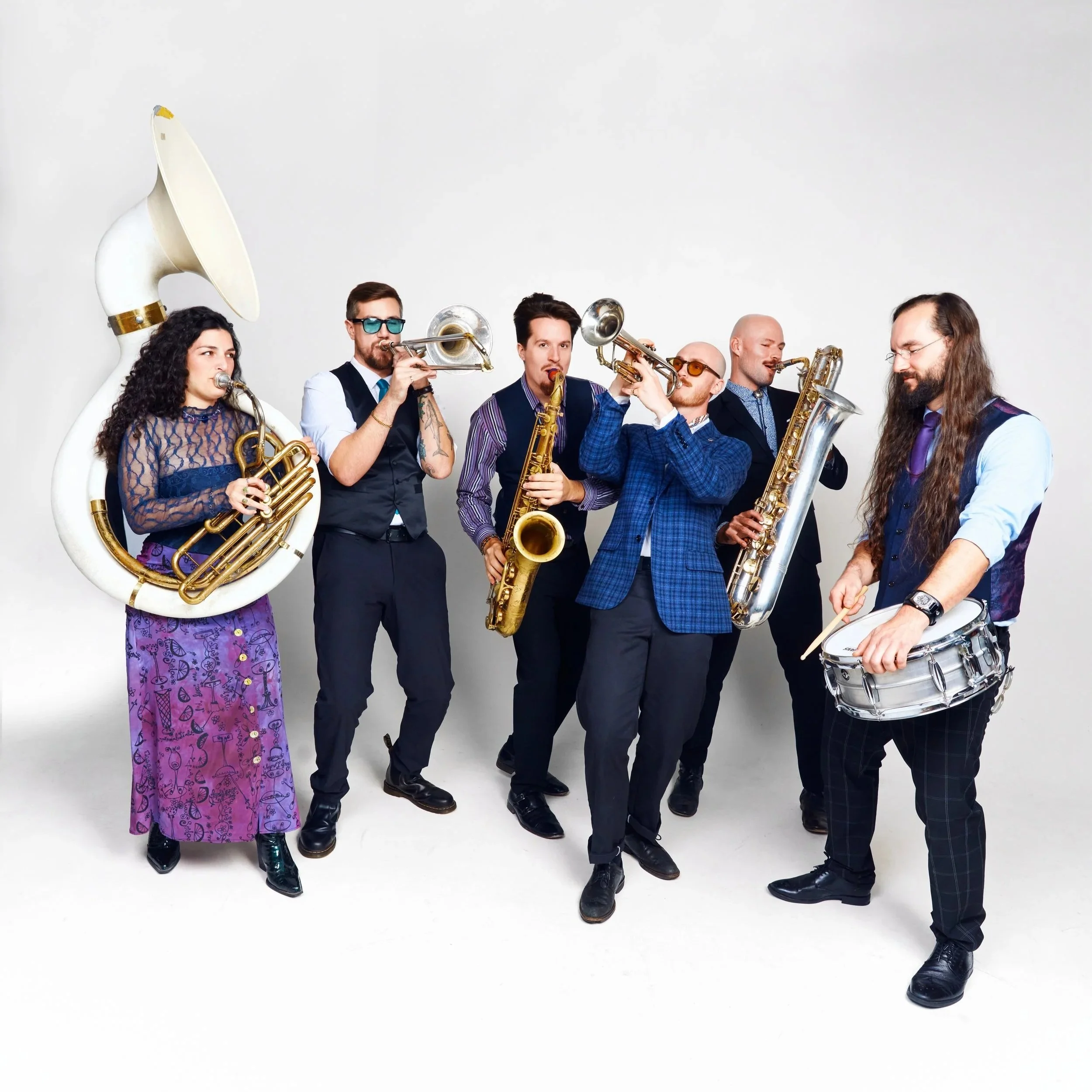 The band dressed to the nines in a fun, funky, and refreshing wedding look. Vests, leather boots, plaid, and blur/purple hues make up the outfits.