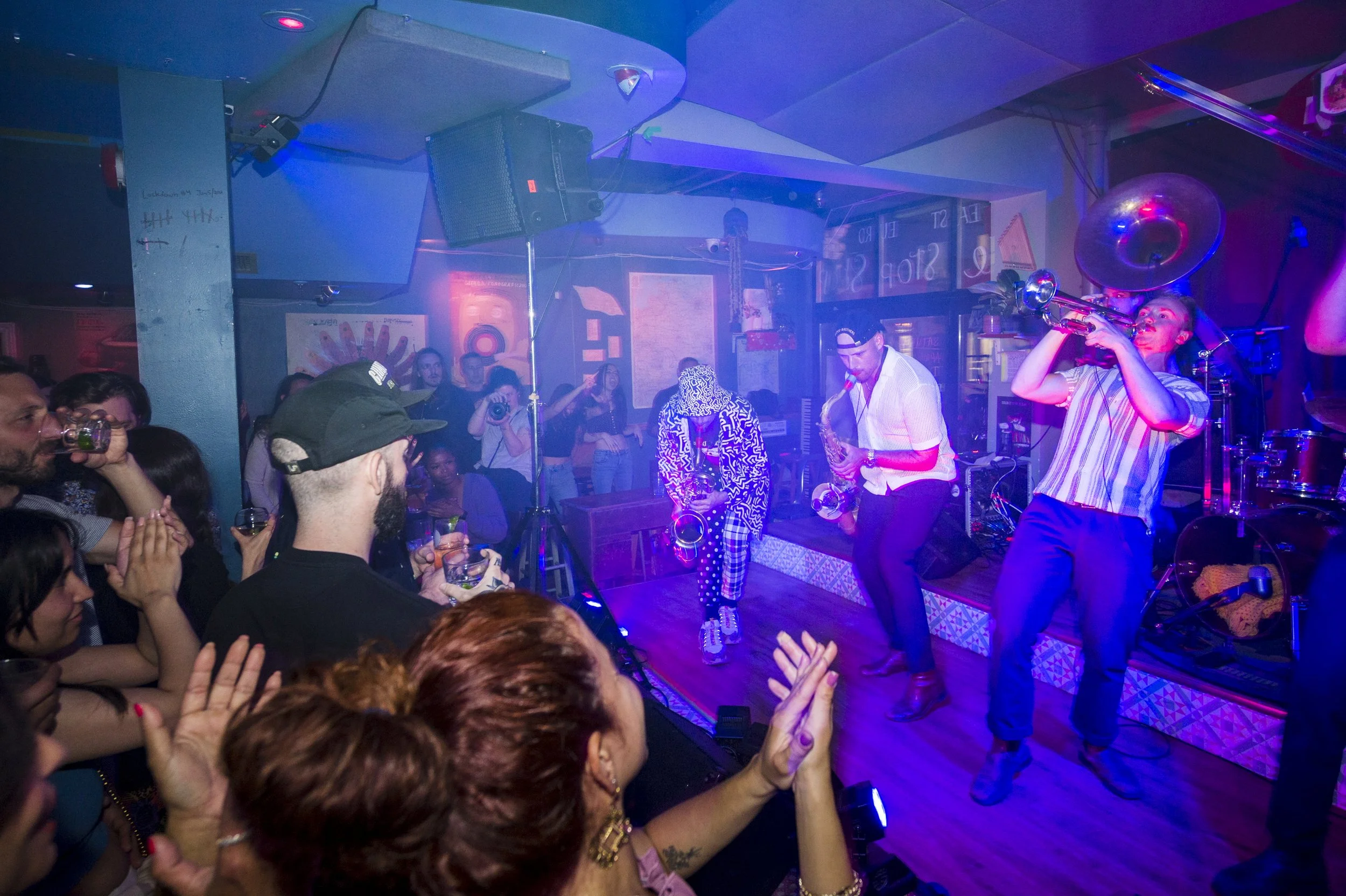 A crowd of people clapping along to Big Smoke Brass on stage. The band is rocking and the people are dancing.