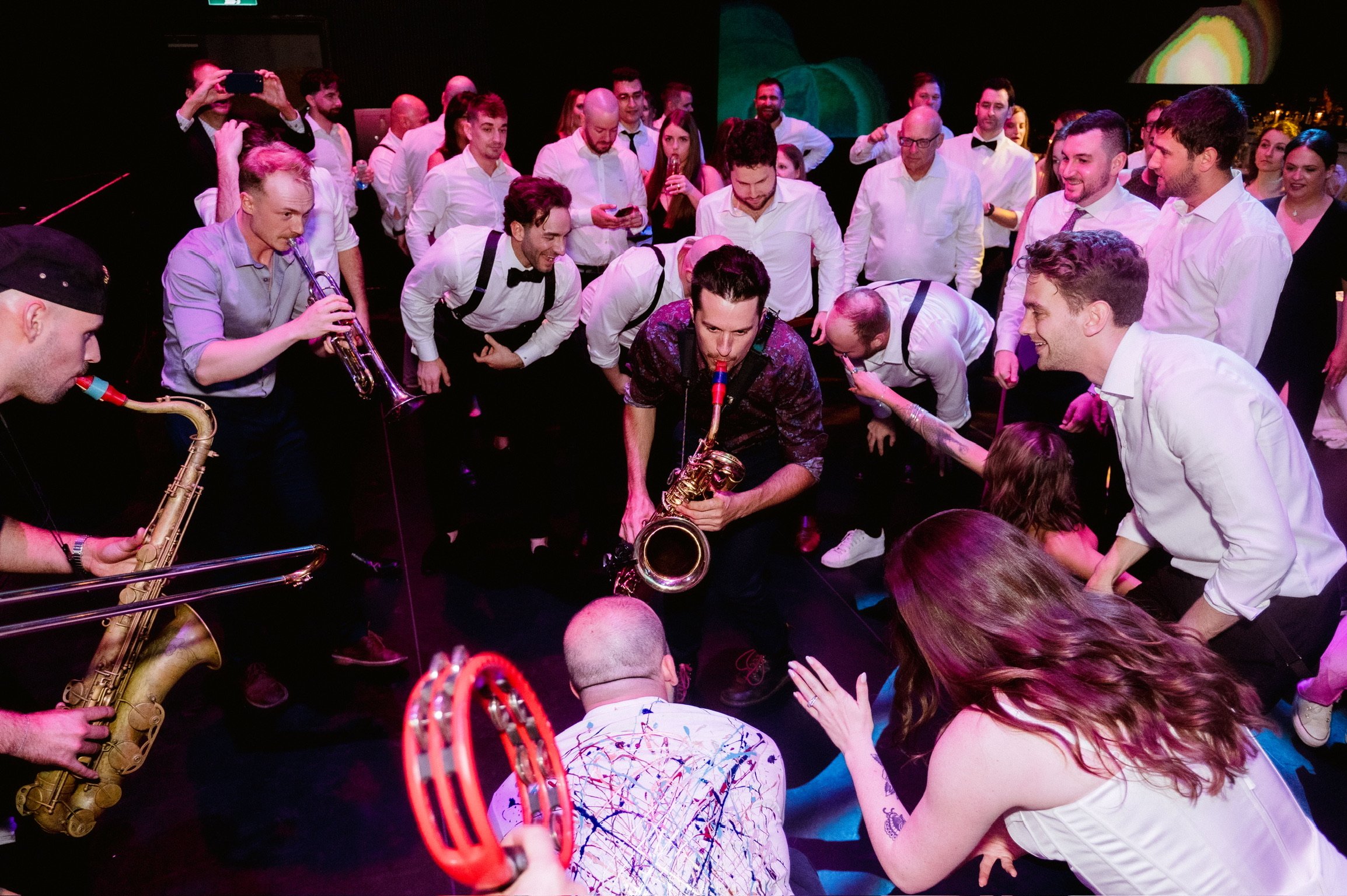 Saxophones and Trumpet playing to the bride, groom, and entire wedding party right in the middle of the dancefloor.