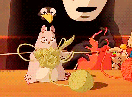 The scene shows BMO and a pink pig character from the animated show 'Adventure Time,' with a black-gloved hand knitting red yarn into a ball.