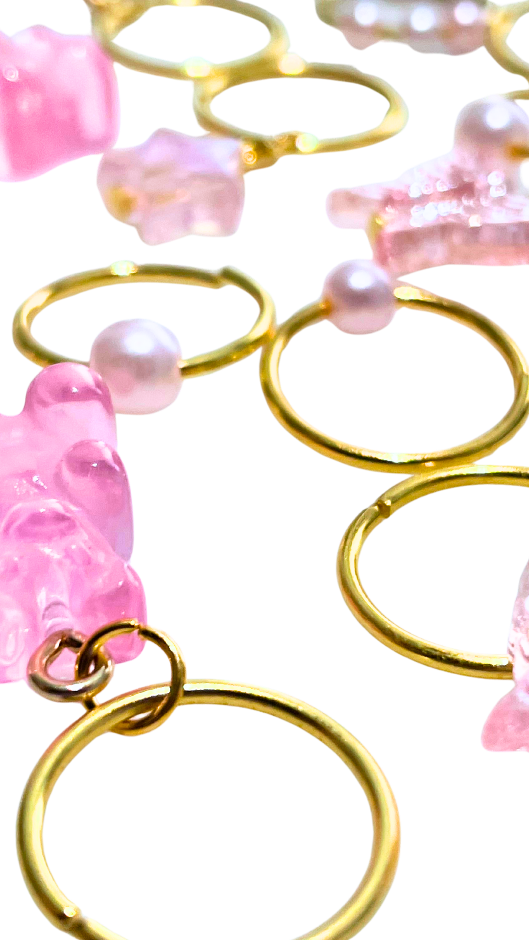 Close-up of pink and pearl-colored jewelry with gold rings and charms.