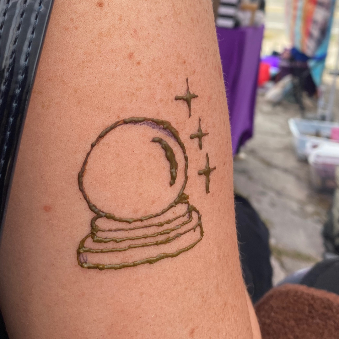 Tattoo of a cat's head, three stars, and three crescent moons on person's upper arm.