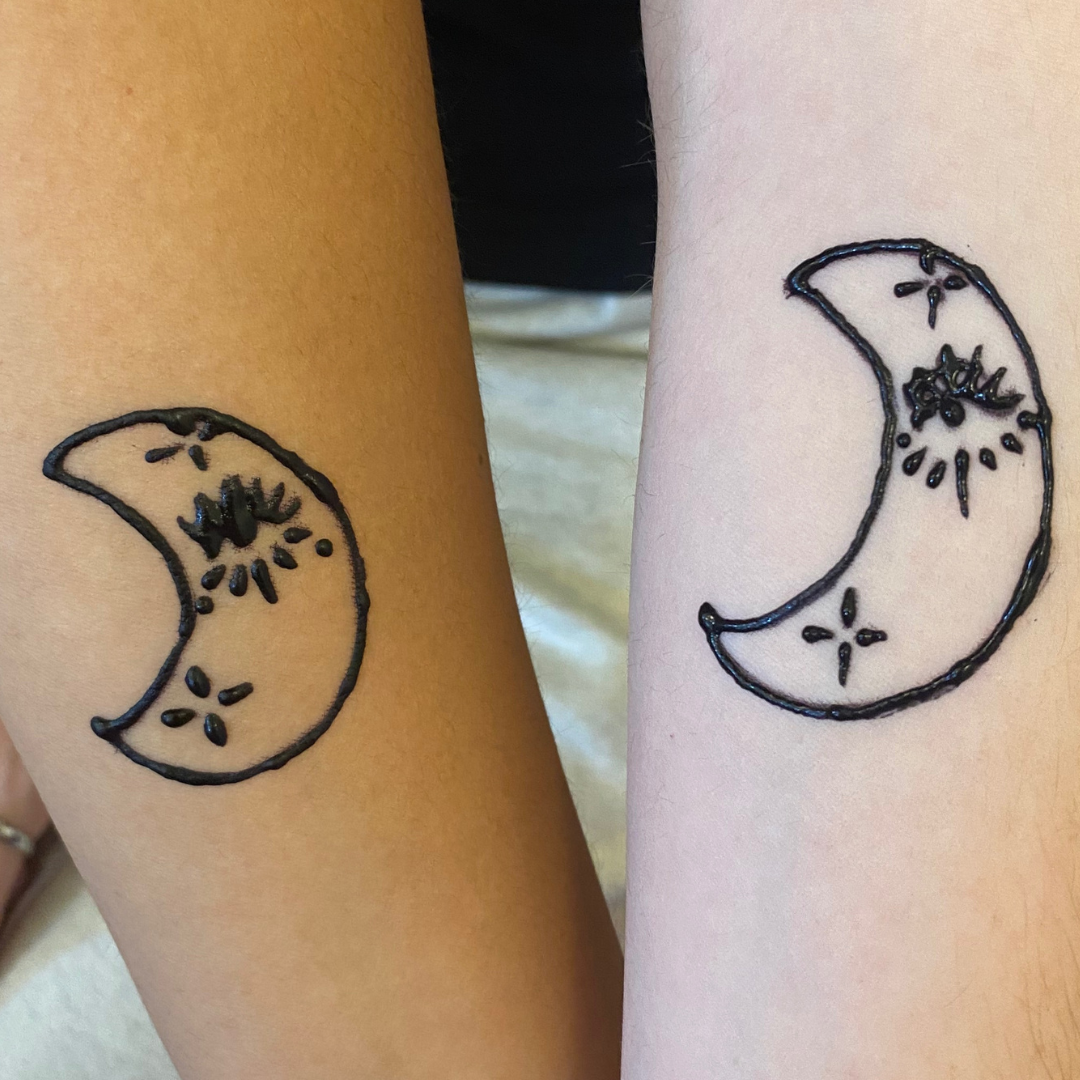 Two different moon phase tattoos on the arms, outlined in black ink, with crescent and new moon shapes.
