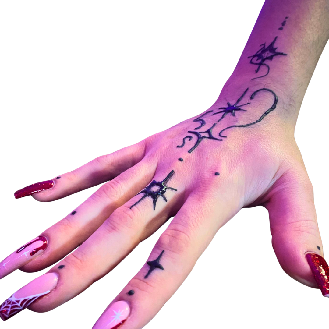 Close-up of a hand with black star-themed tattoos and decorated nails with red and white designs.