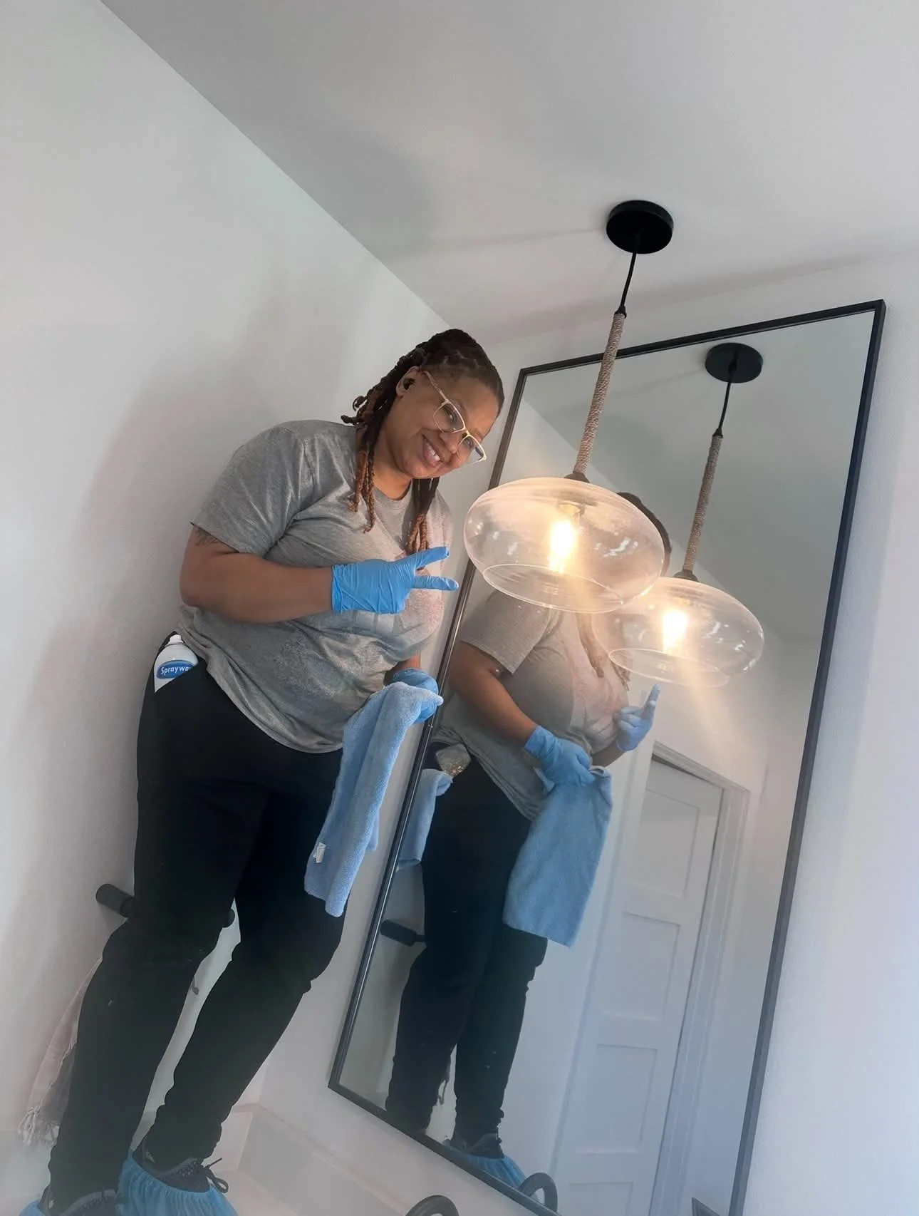 Professional cleaner wiping and detailing a bathroom mirror and light fixtures.