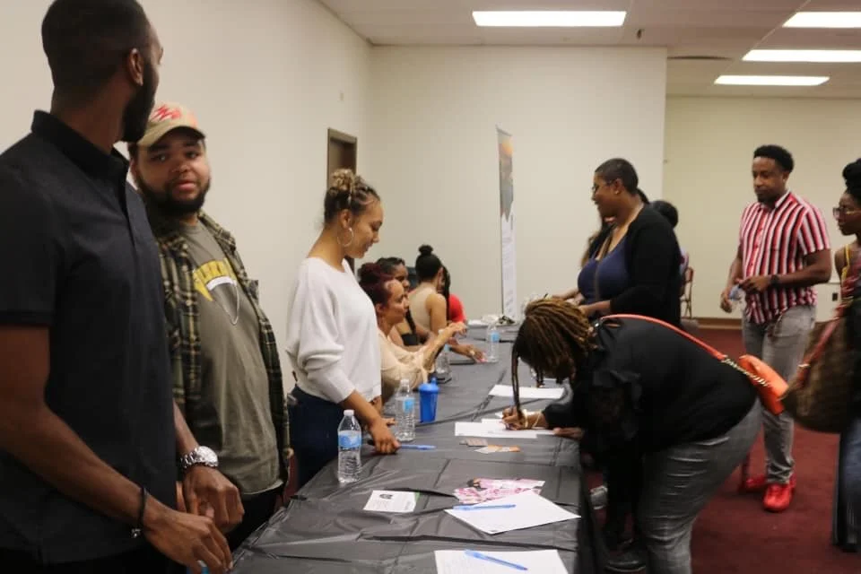 People at a registration or sign-in table in a community center or event hall.