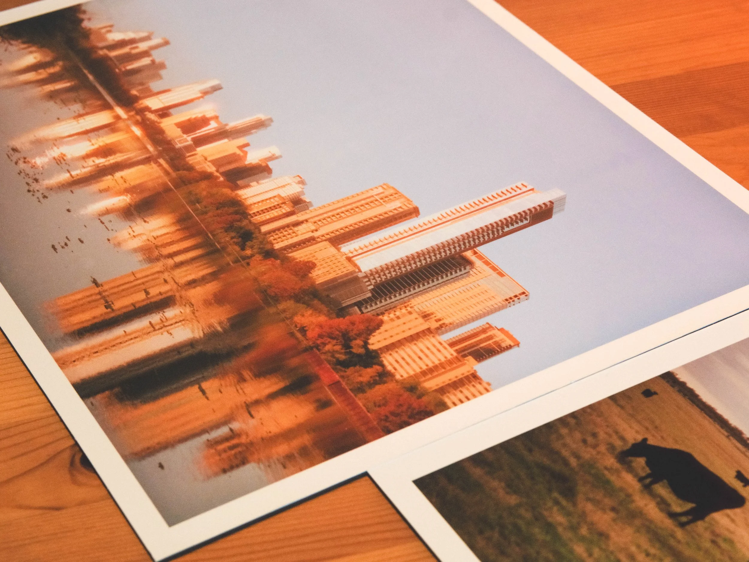 A printed photograph of a city skyline with tall skyscrapers during sunset, lying on a wooden surface.
