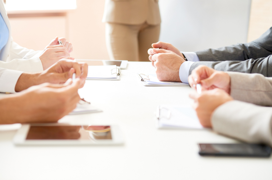 People having a business meeting around a table with clipboards and tablets.