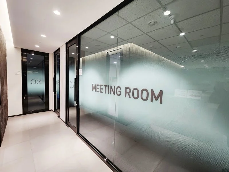 유리문이 있는 회의실 출입구, 'MEETING ROOM'과 'C04' 표시된 유리 벽과 문의 모습