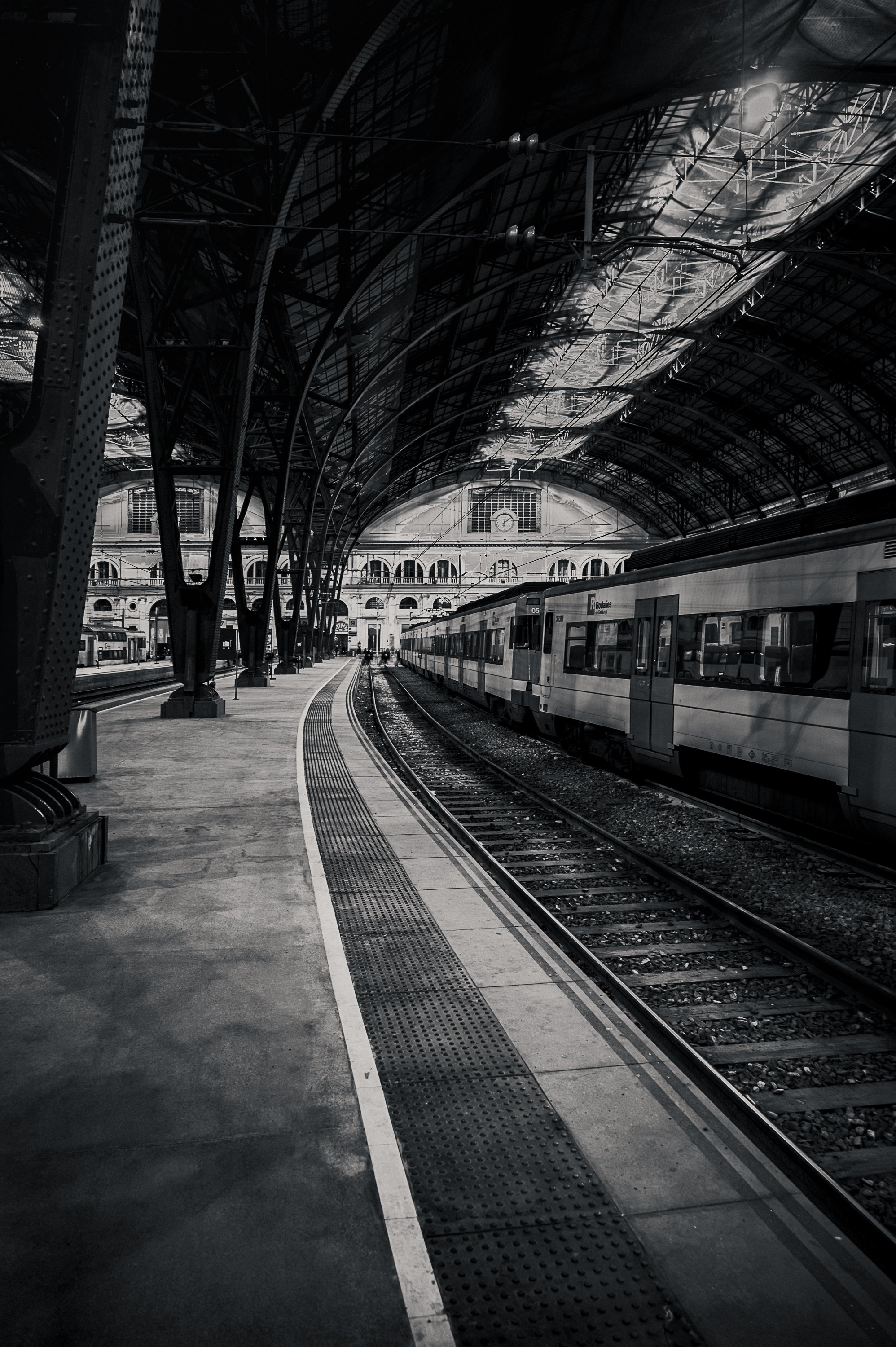 Waiting train and tracks beneath the dark iron-and-glass station roof at night.