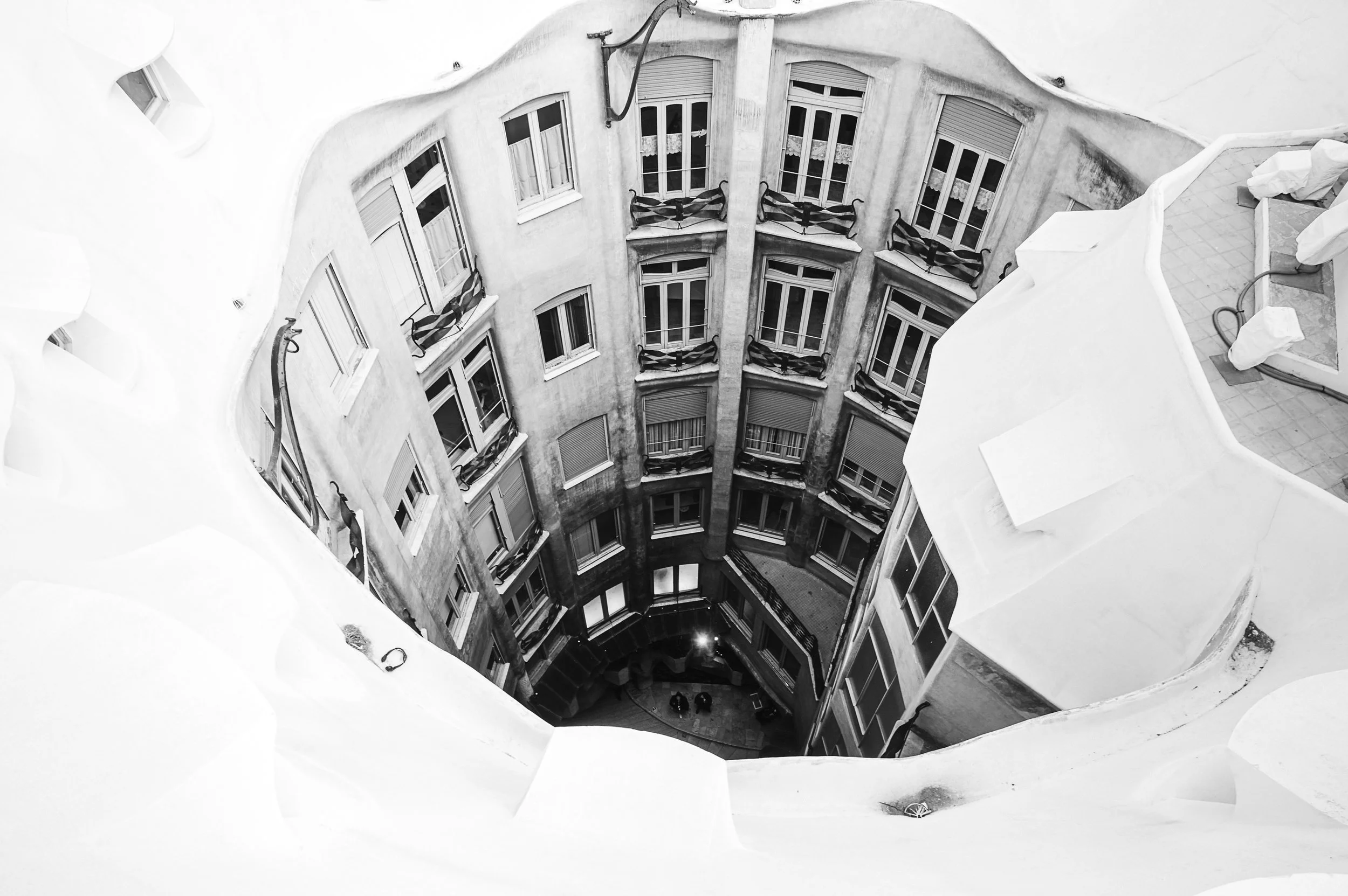 View down into Casa Milà’s courtyard, framed by curved white edges and balconies.
