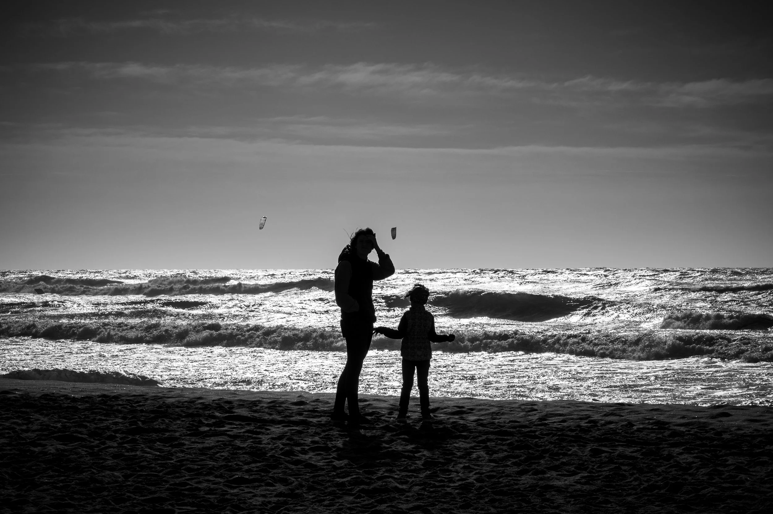 Two figures standing at the edge of light and sea