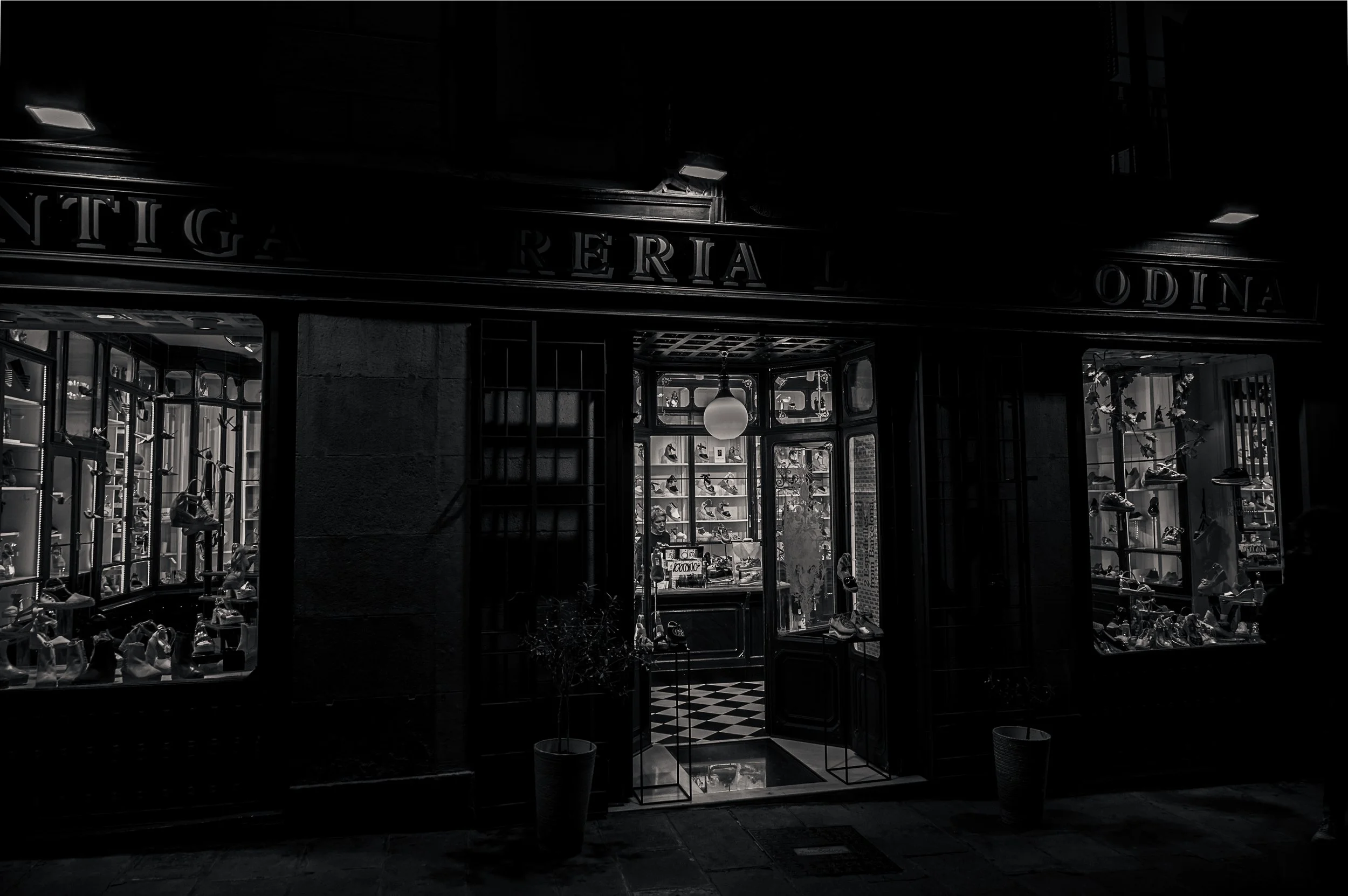 Historic candle shop in Barcelona glowing against a dark street facade at night.