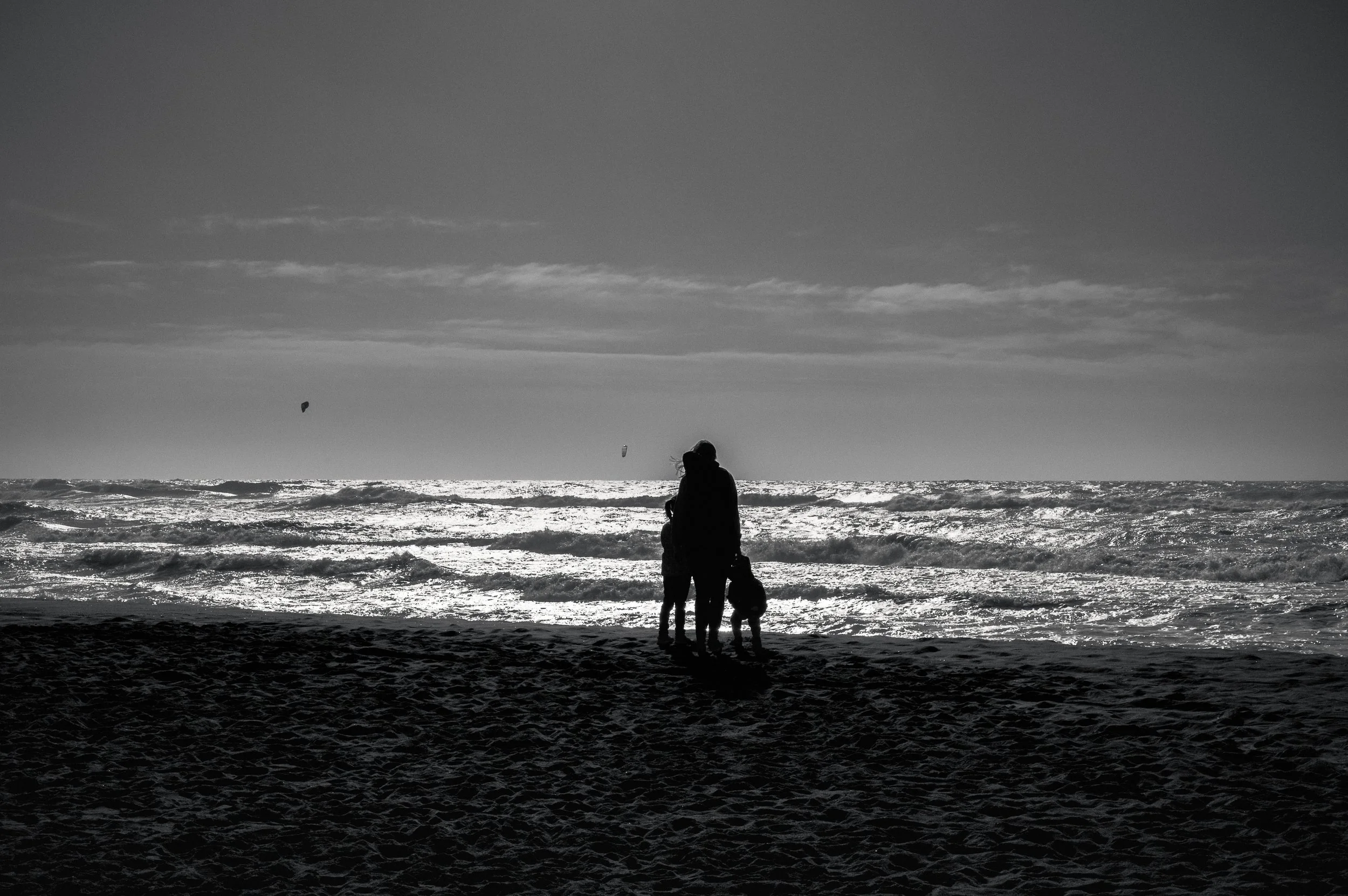 Three figures facing sea and silence