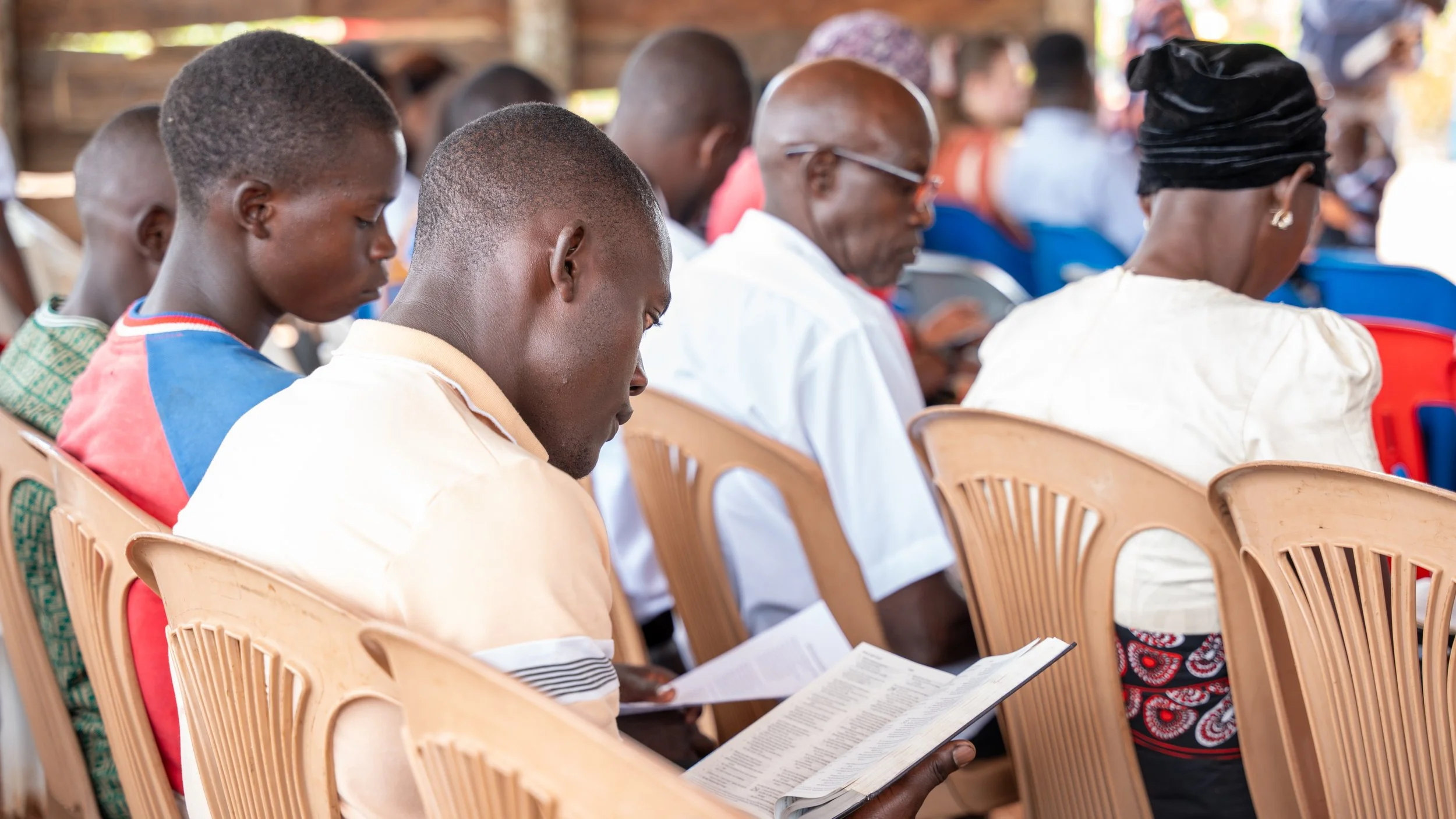 People sitting in chairs, reading and listening during a service at LBC.