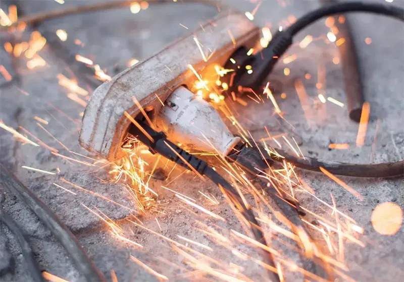 An electric grinder cutting through metal, producing sparks.