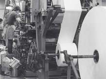 Drei Männer in Schutzhelmen, die an einer großen Maschine in einer Fabrik arbeiten.