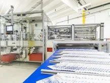 Automatisierte Maschine in einer Produktionshalle, die medizinische Masken herstellt.
