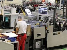 Mitarbeiter arbeitet in einer industriellen Fertigungsanlage mit verschiedenen Maschinen und Computern.