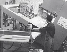Mensch arbeitet an einem großen Druckmaschinen oder industriellen Gerät in einer Fabrikhalle.