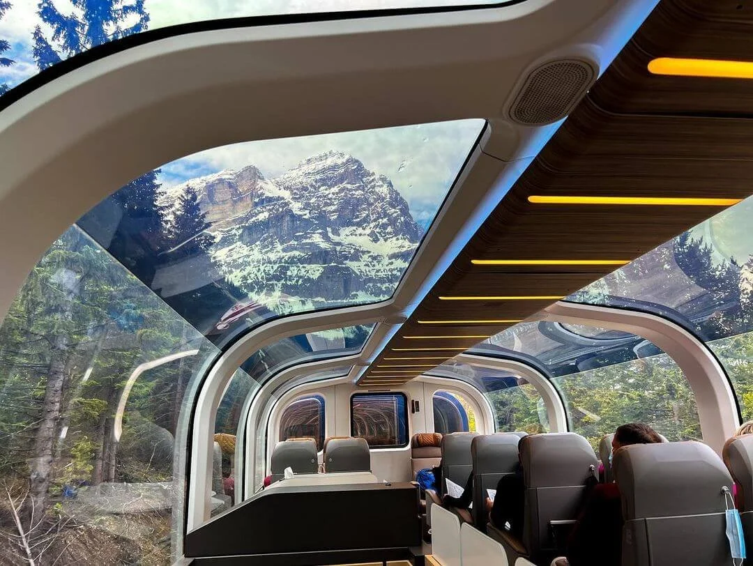 Rocky Mountaineer luxury train with glass-domed roof traveling through the Canadian Rockies near Banff