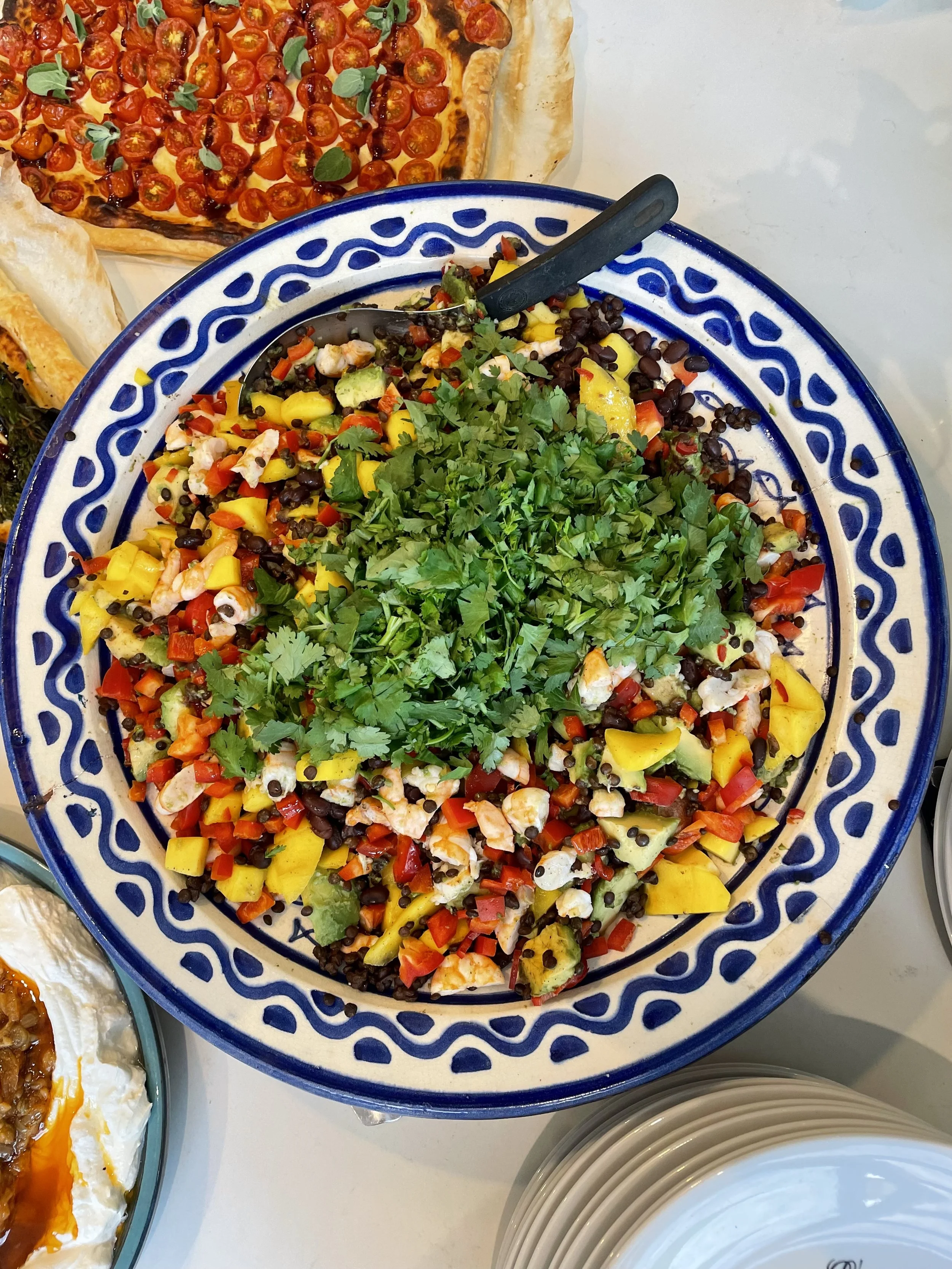 Colorful chopped vegetable salad topped with fresh cilantro in a decorative blue and white bowl.