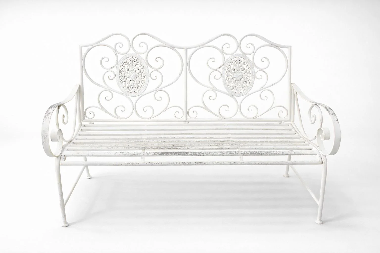 White ornate metal garden bench with decorative scrollwork and floral design on backrest, against a plain white background.
