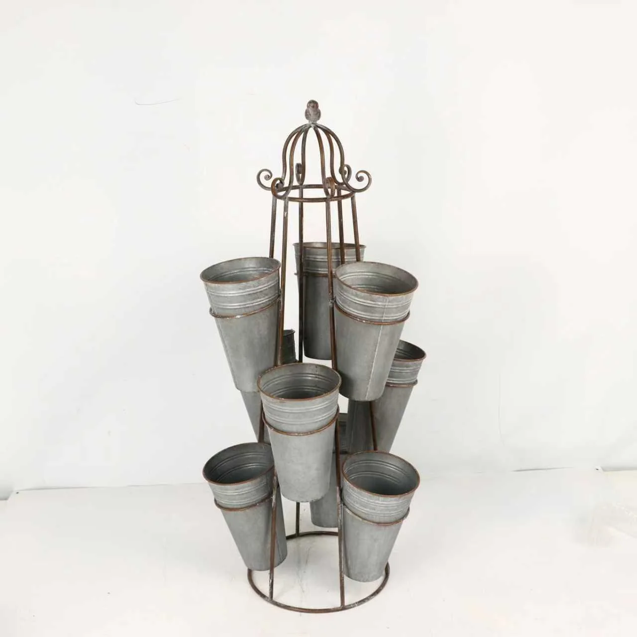 A metal caddy with a decorative top holding eight empty metal buckets.