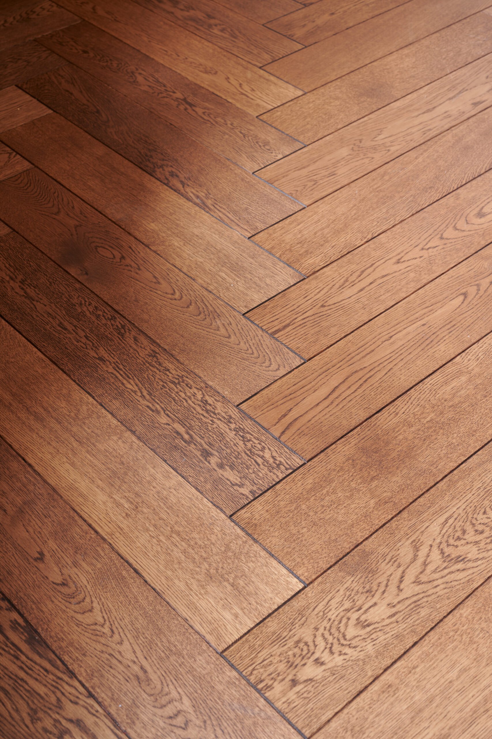 Close-up view of a wooden herringbone-patterned hardwood floor.