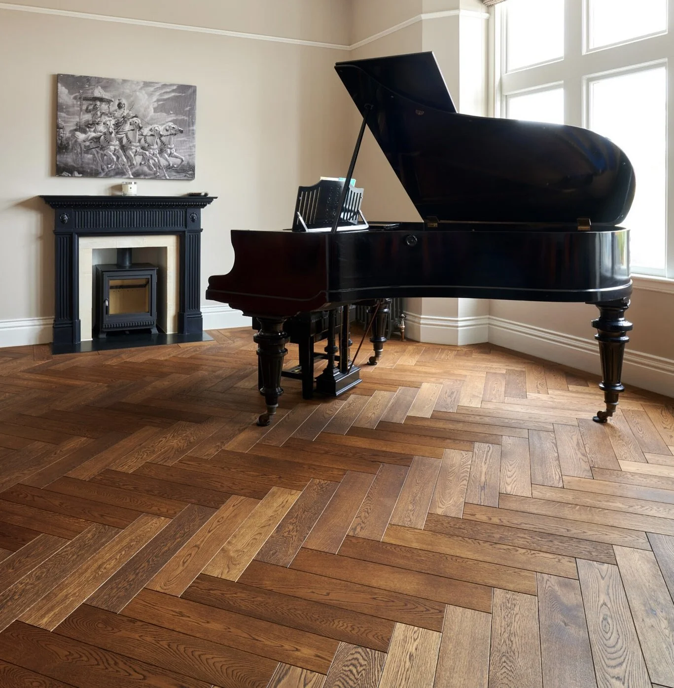 A black grand piano in a well-lit room with a window and hardwood herringbone floor, above a fireplace with a black mantel and a monochrome painting of horse riders on the wall.