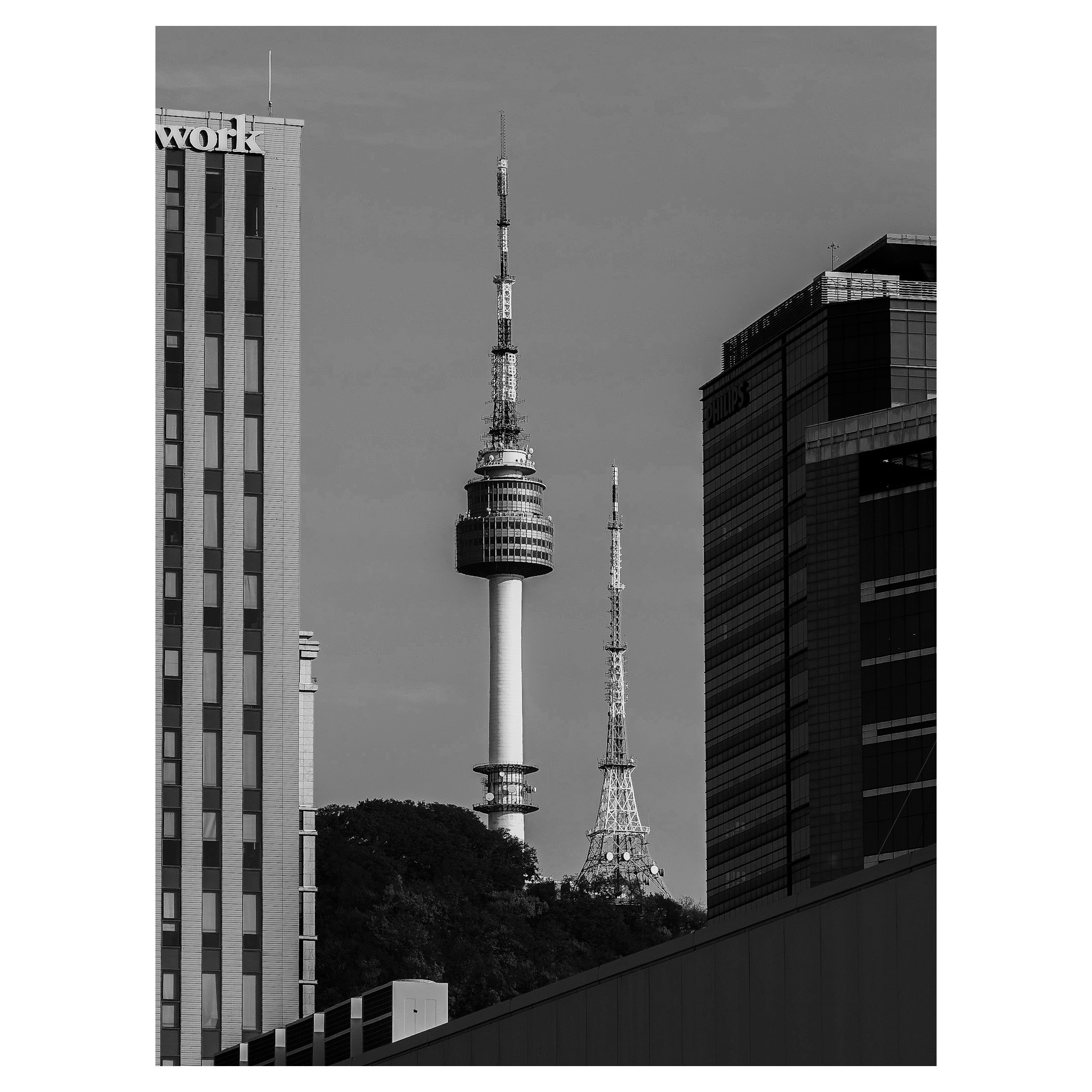 Black and white photo of cityscape with high-rise buildings and a tower with an observation deck and antenna at the center.