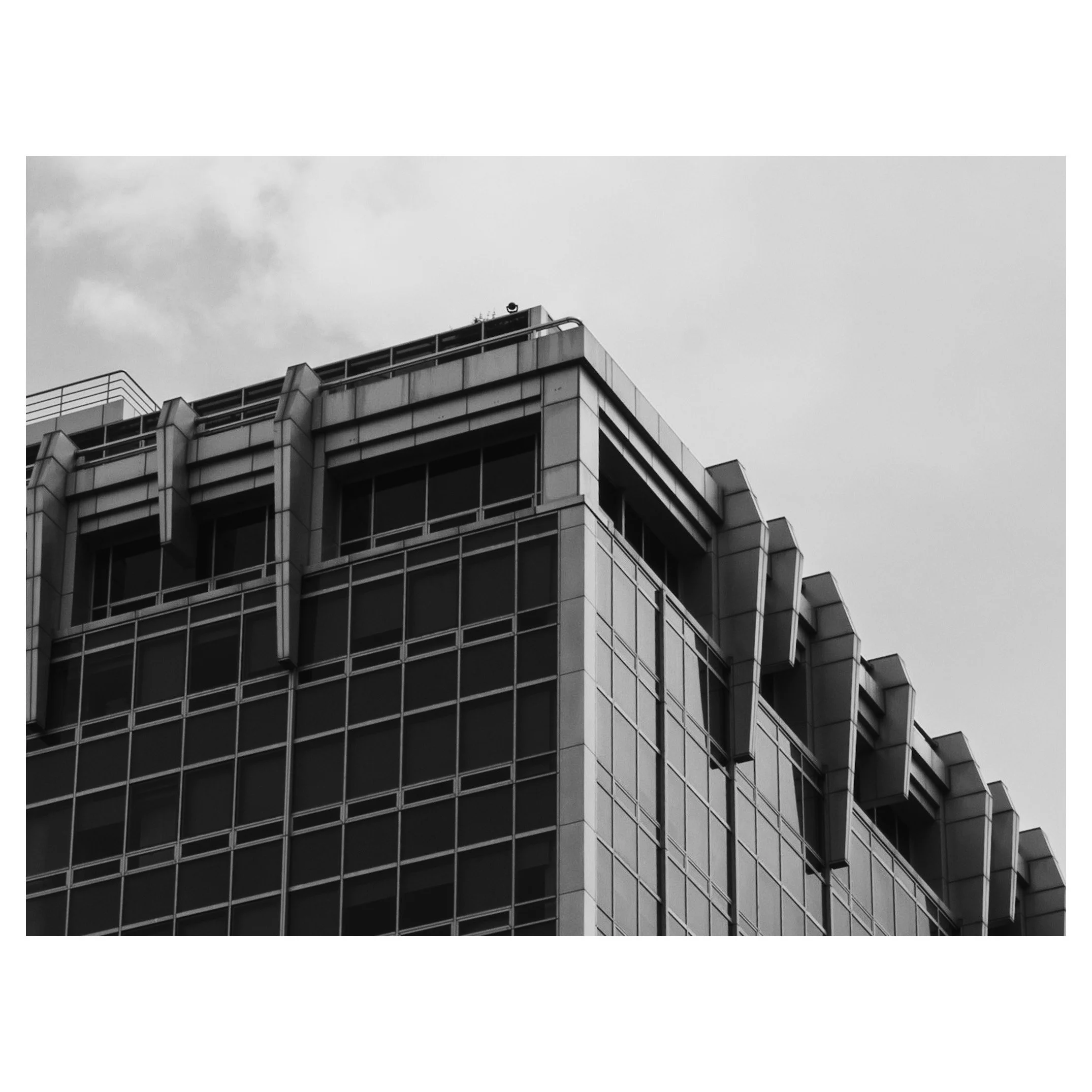 Black and white photo of a modern multi-story building with glass windows and angular architectural details.