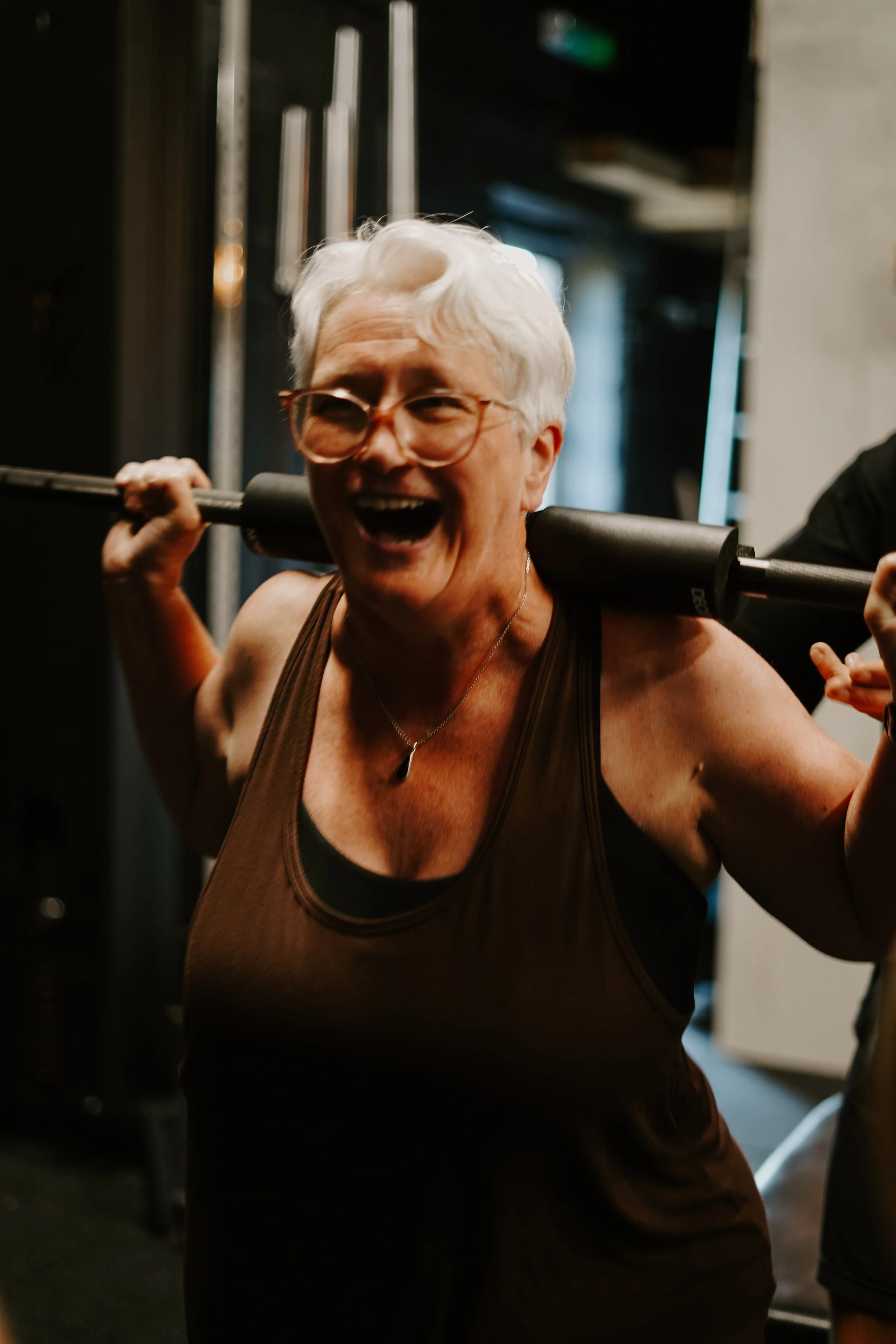 Older woman smiling during a training session in a gym.