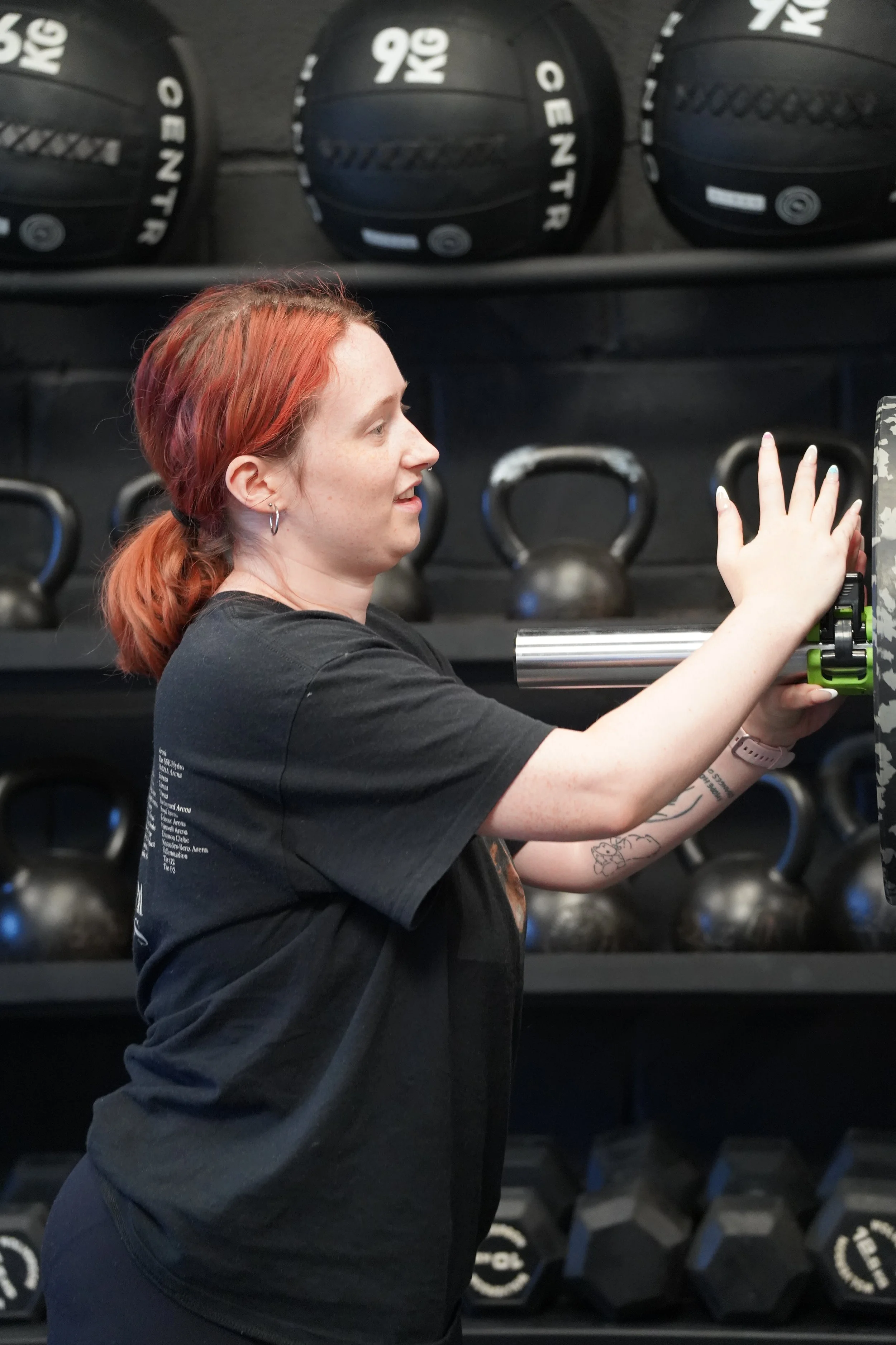 Woman adding weight plates to a barbell in a gym.