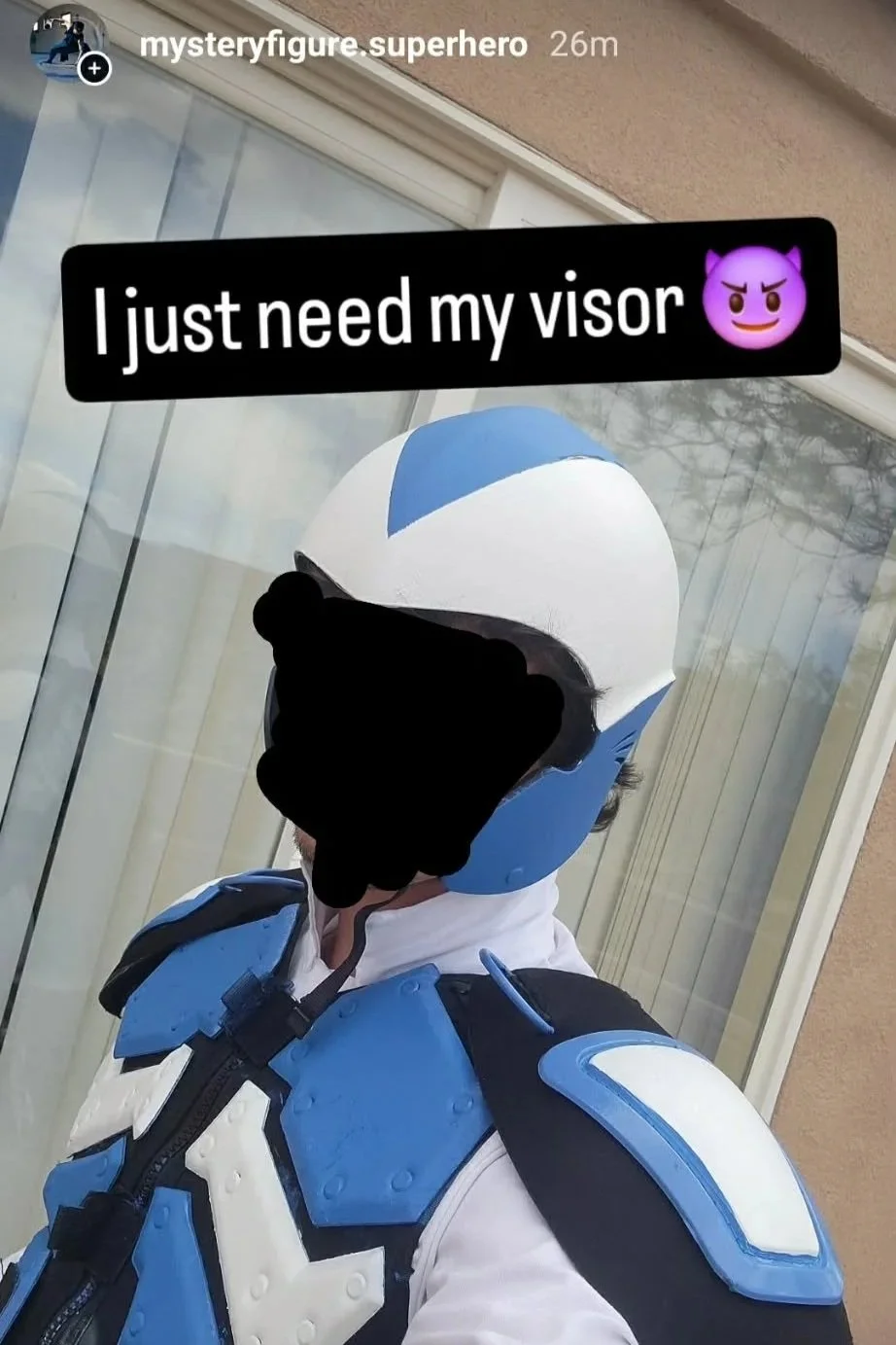 A person dressed as a blue and white superhero with a helmet, standing outside near a window. The face is obscured with a black scribble. The caption states, 'I just need my visor' with an purple devil emoji.