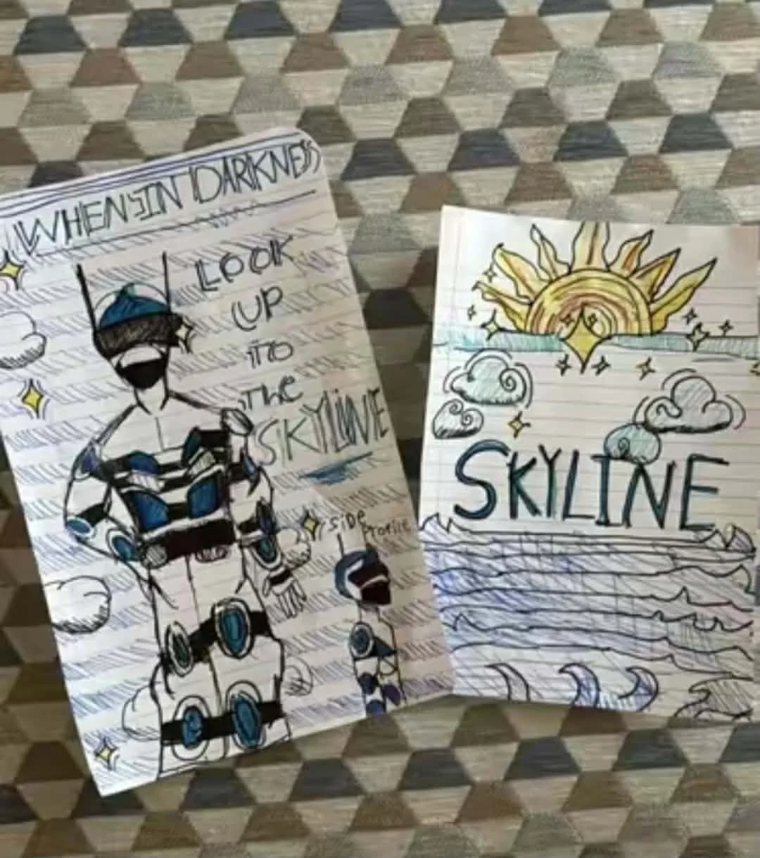 Hand-drawn illustrations on two sheets of paper. The left sheet features a person in striped clothing with text that reads 'When's in darkness look up to the skyline.' The right sheet shows a rising sun with clouds and birds, and the word 'skyline' w