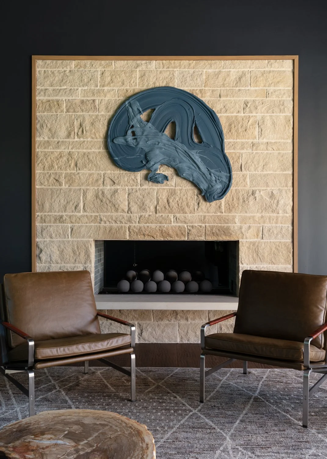 A contemporary stone fireplace and two leather arm charis with chrome finish – Interior Design Forth Worth Texas