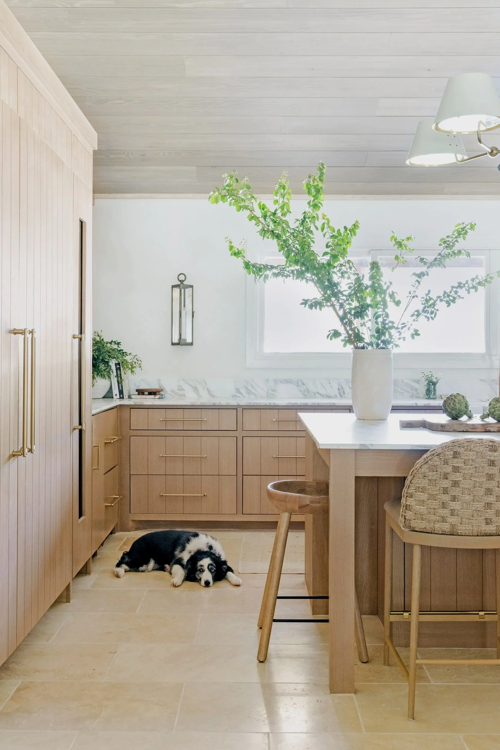 A modern and bright wooden kitchen with white marble backsplash, a dog resting on the floor tiles – Forth Worth Interior Designer Emily Gilbert