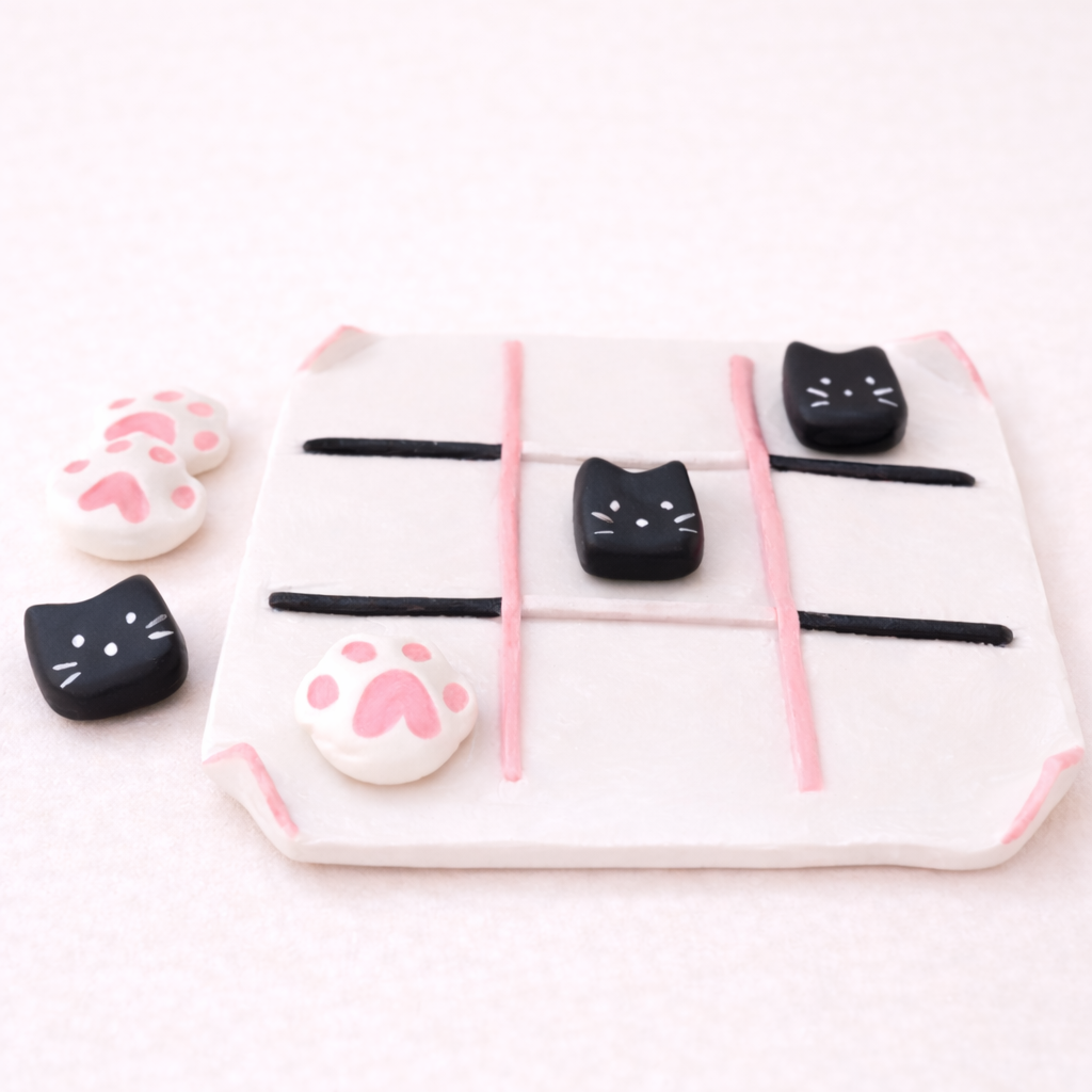 Jeu de morpion avec des pièces en forme de chats noirs et de pattes de chat roses et blanches.