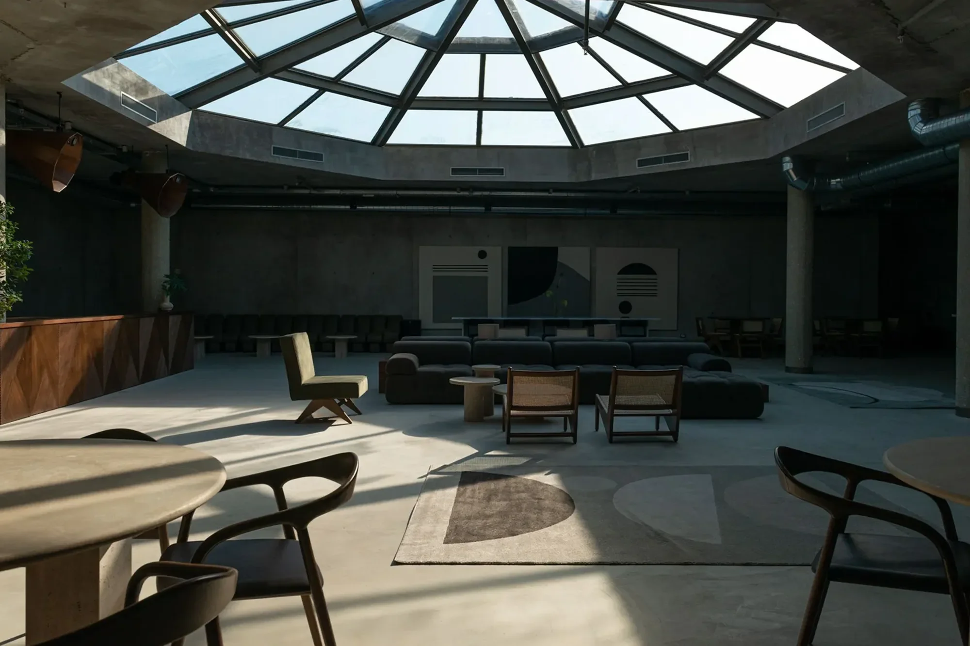 Interior di un soggiorno moderno con un soffitto in vetro a cupola, arredamento minimalista, tappeto, sedie e divani, con luci naturali provenienti dal soffitto.