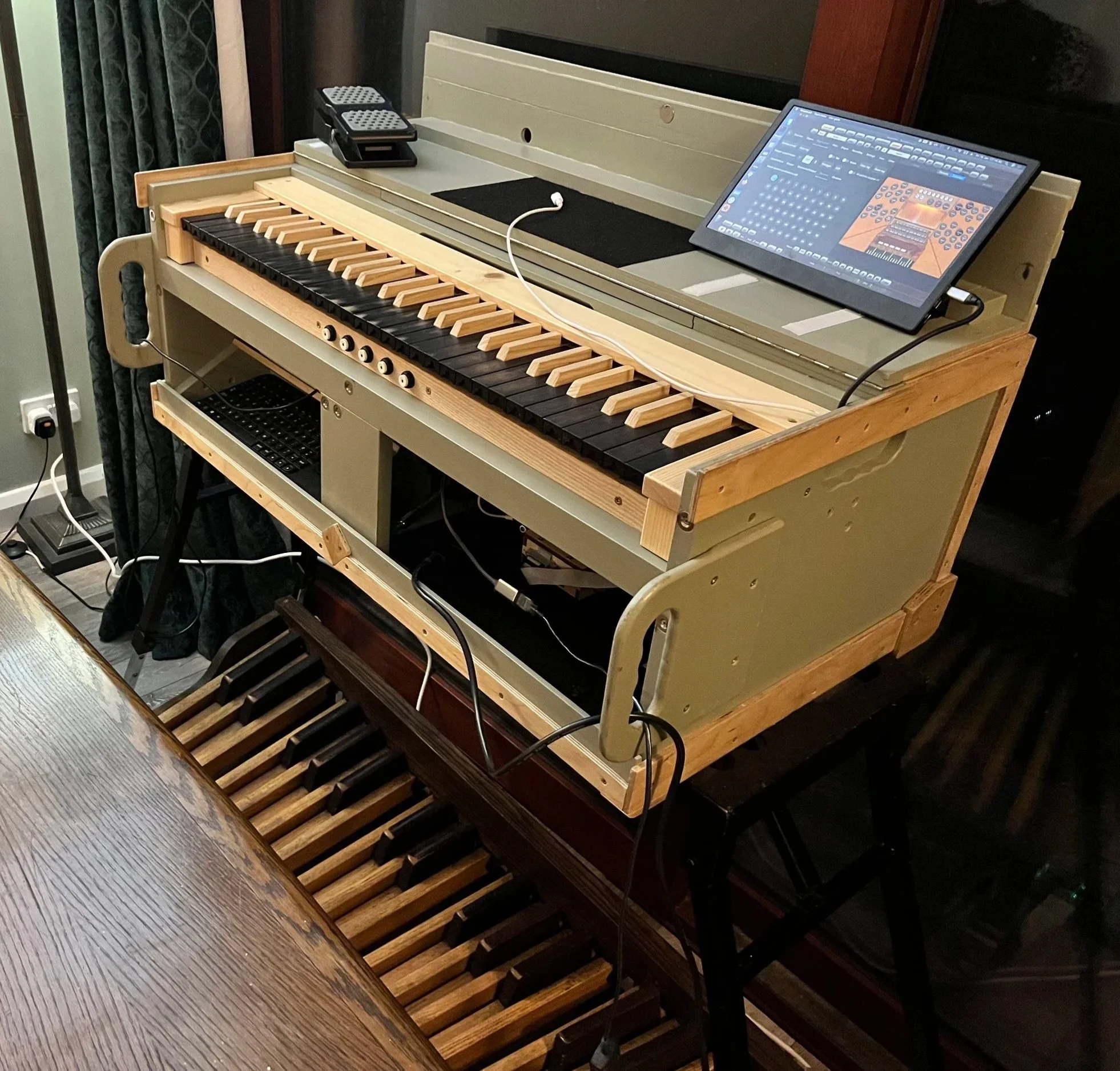A digital keyboard and an upright piano in a home setting, with electronic equipment and cables.