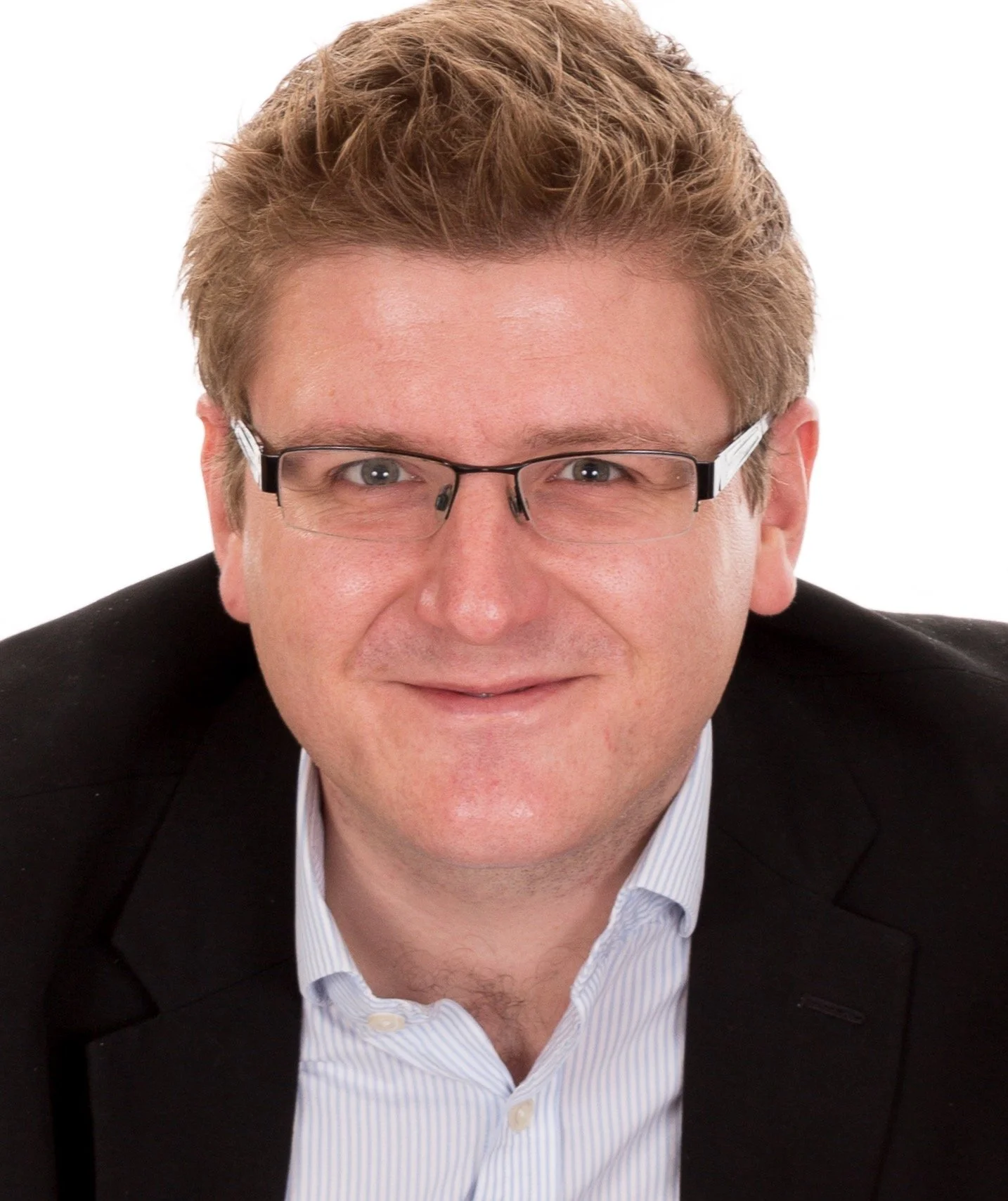 Headshot of a man wearing glasses, a black blazer, and a light blue striped shirt, smiling against a white background.