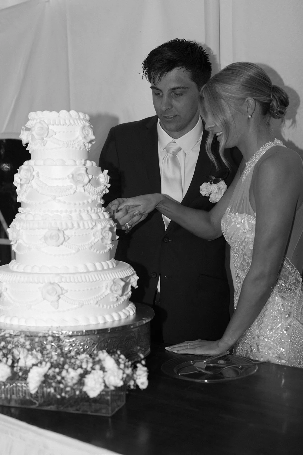 A bride and groom cutting a wedding cake together at their reception.