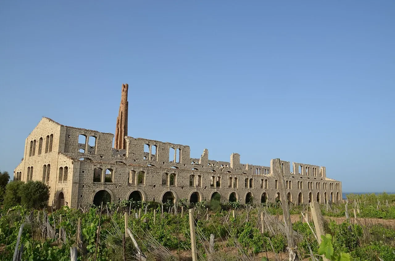 The roofless stone walls, arched openings and tall chimney of Fornace Penna near Sampieri